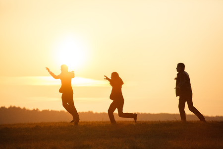 Men run across the field in the lights of sunsetの写真素材