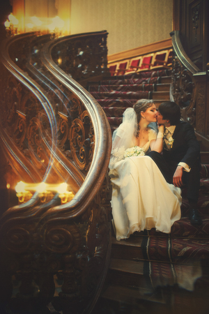 Newlyweds sits on the old wooden stairs with curved elements in the theatreの写真素材