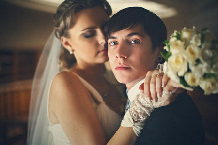 Groom looks serious while stands in the hugs of brideの写真素材