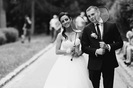 Bride and groom pose with tennis-rackets in their armsの写真素材
