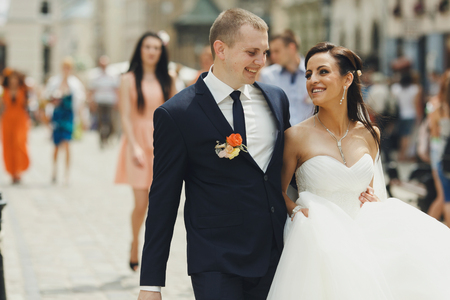 Groom leads a bride around the city holding her waistの写真素材