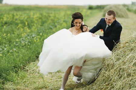 Groom catches bride on the hayの写真素材