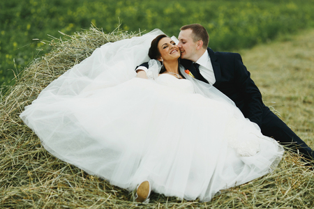 Newlyweds having fun on the bottle of hayの写真素材