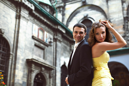 Man and woman stands back to back in the front of old cathedralの写真素材