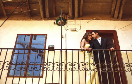 Man and woman in yellow stand thoughtfully leaning on the balconyの写真素材