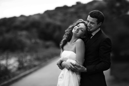 Lady rests on man's shoulder while he hugs her from behindの写真素材