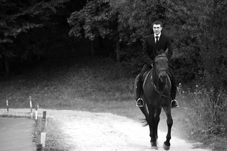 Man in black suit rides a horseの写真素材