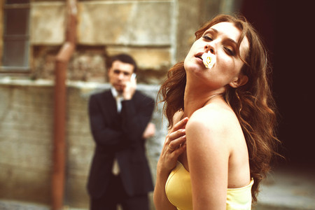 Woman looks seductive holding rose in her mouthの写真素材