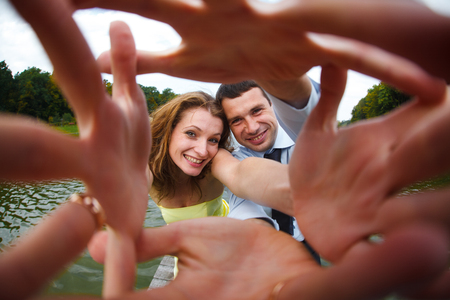 Man and woman smile reaching their hands out to the cameraの写真素材