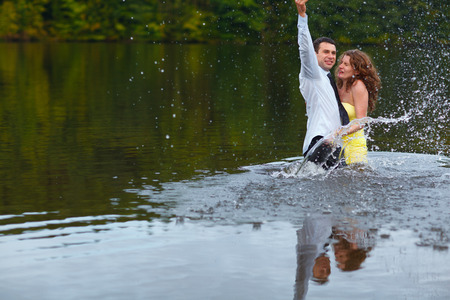 Man splashes water hugging woman in yellow dressの写真素材