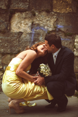 Couple sits squatting before old stone wallの写真素材