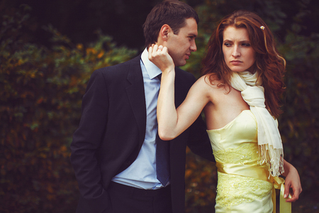 Tired lady touches man's face while he hugs herの写真素材