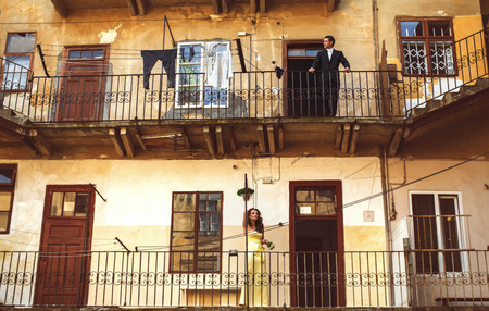 Man and woman stand thoughtfully on balconies on the different floorsの写真素材