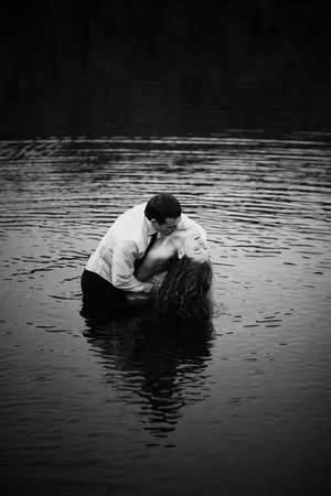 Man leans lady over standing in waterの写真素材