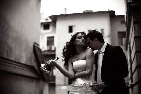 Groom kisses bride's shoulder while she looks in the cameraの写真素材