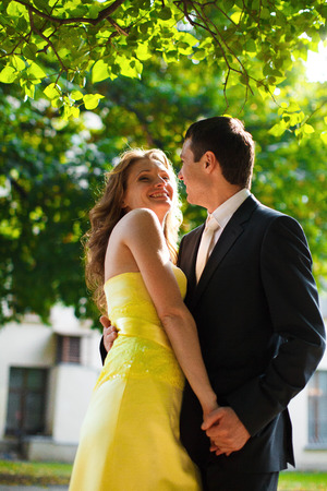 Sun highlights woman in yellow dress while she hugs a manの写真素材