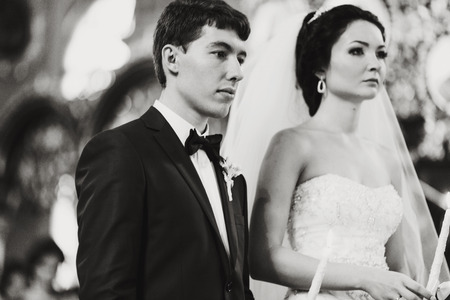 Newlyweds look musing during a ceremony in the churchの写真素材