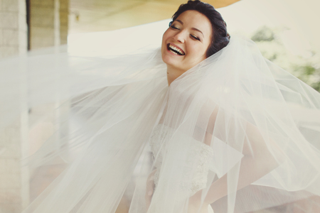 Bride laughs while wind plays with her veilの写真素材