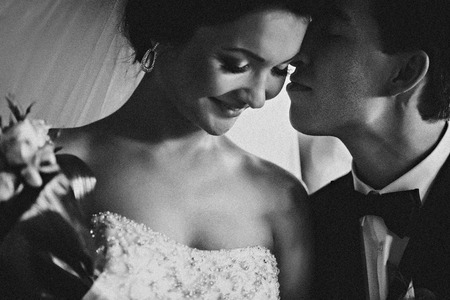 Bride looks shy being kissed by the groomの写真素材