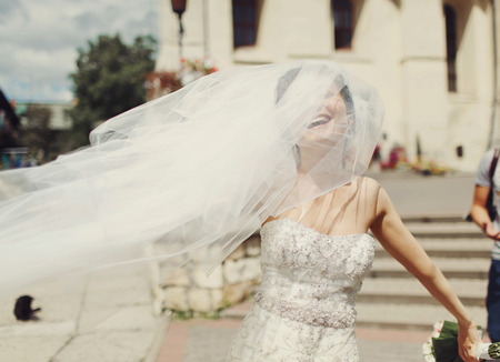 Bride laughs being covered with a veil during a walk aroundの写真素材