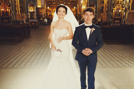 Smiling bride and groom walk out of the churchの写真素材