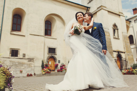 A view from below on the gorgeous wedding couple standing in the front of old cathedralの写真素材