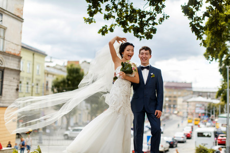 Bride and groom smile posing in the front of a great cityscape