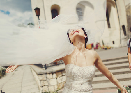 Bride's veil flies up while she walks around a cityの写真素材