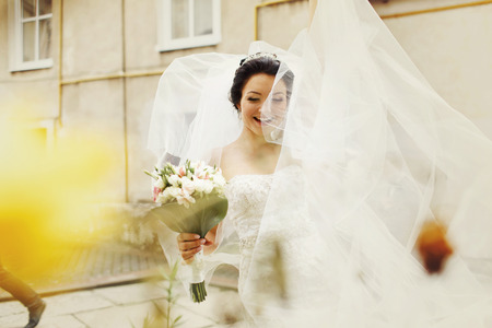 A picture of a bride playing with her veil and holding her wedding bouquetの写真素材