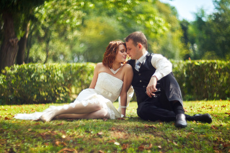 Trust and kiss - bride and groom sit on the grass in parkの写真素材