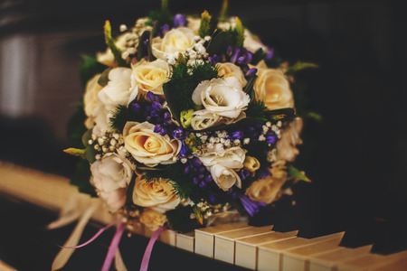 A wonderful bride's bouquet of white roses and violets lies on the pianoの写真素材