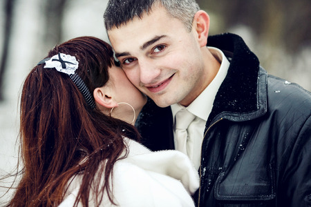 A handsome groom smiles while a bride hides her face under his chinの写真素材