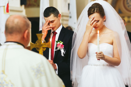 Newlyweds cross themselves praying in the churchの写真素材