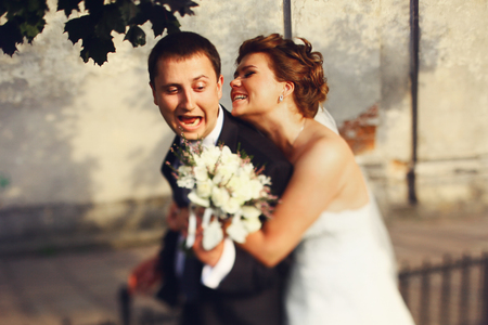 Groom laughs while bride tries to hold him tightlyの写真素材