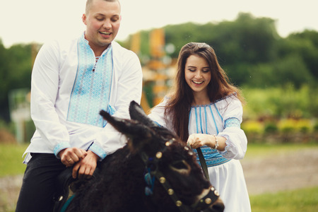 Bride dressed in Ukrainian ethnic dress leads a donkey with a groomの写真素材
