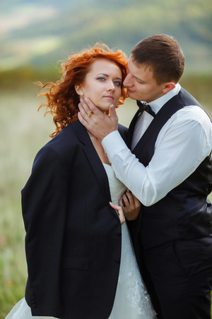 Bride looks gorgeous while groom kisses her cheek holding her chinの写真素材