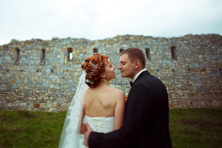 Newlyweds look at each other standing before an old wallの写真素材