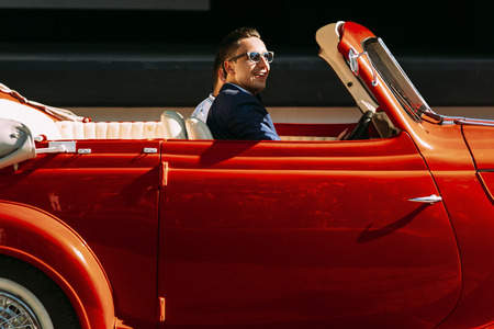 Groom with a friend in the old-fashioned carの写真素材