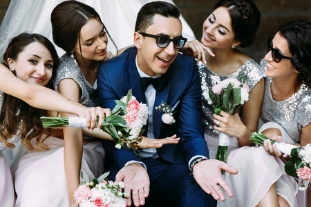 Handsome groom surrounded by beautiful bridesmaidsの写真素材