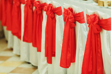 Chairs in restaurant covered with white cloth and red bowsの写真素材