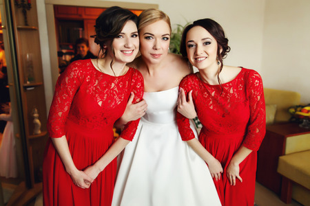 Bride holds hands of pretty bridesmaids dressed in redの写真素材