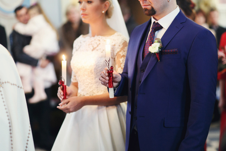 Bride and groom hold candles during an engement ceremonyの写真素材