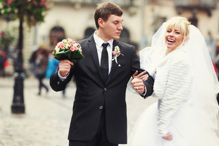 Bride links her arm through groom's arm walking around an old part of the cityの写真素材