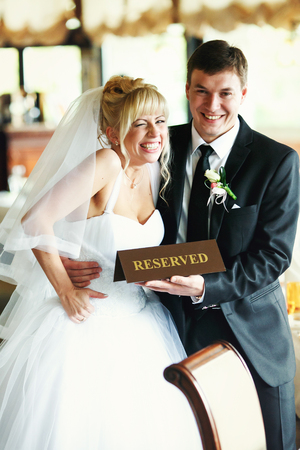 Bride laugh while groom holds a plate 'Reserved' before herの写真素材