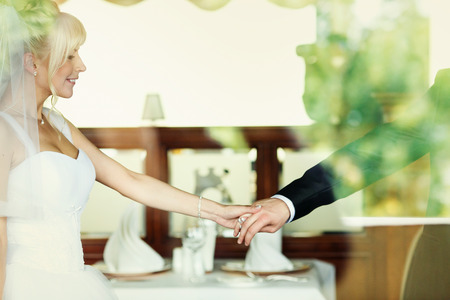 Bride walks around a restaurant holding groom's handの写真素材