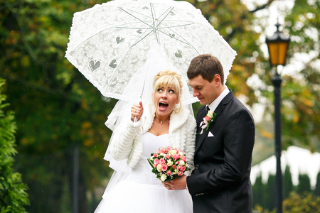 Bride screams looking at her veil hooked on the umbrellaの写真素材