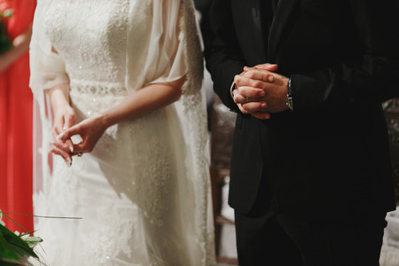 A close-up of wedding couple's hands while they pray in churchの写真素材
