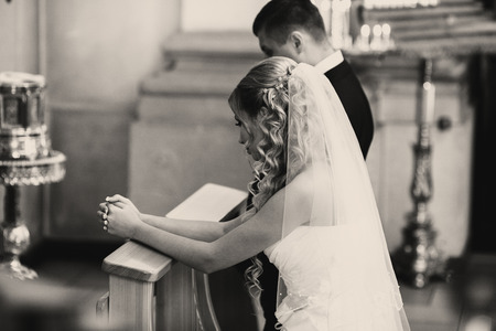 Bride and groom pray standing on the knees during an engagement ceremonyの写真素材