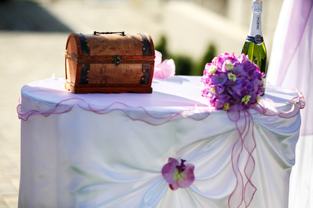 Little wooden trunk stands on a table behind a bottle of champagneの写真素材