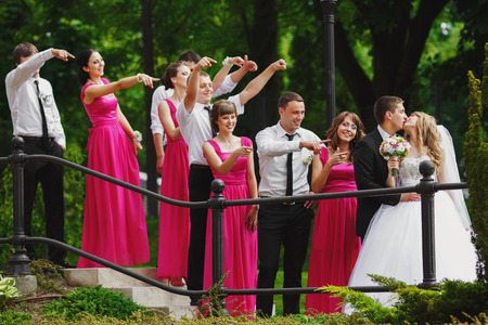 Bridesmaids and groomsmen stare at a kissing wedding coupleの写真素材